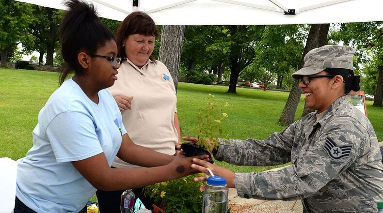 Raejean Smith, Five River Metro Parks volunteer, gives a Lantana plant to Staff Sgt. Cassandra Mena, United States Air Force School of Aerospace Medicine industrial hygiene laboratory technician, during the Pollinator Expo held at the Wright Brothers Memorial located outside Wright-Patterson Air Force Base June 21. Numerous local organizations were on site to highlight the work they do to protect pollinators and their habitats. (U.S. Air Force photo/Michelle Gigante)