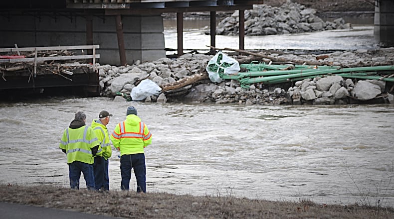 Workers watch the Great Miami River near the Keowee Street Bridge.  A  large water main break on Feb. 14, 2019 cut water service to much of the County and most of it was restored days later.  MARSHALL GORBY / STAFF