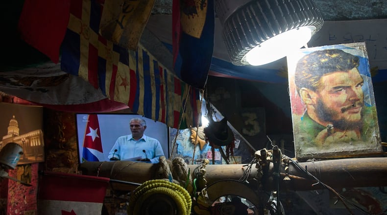 An image of Cuban Revolutionary hero Ernesto "Che" Guevara stands next to a TV showing Cuban President Miguel Diaz-Canel speaking, inside a souvenir shop in Havana, Cuba, Friday, March 13, 2026. (AP Photo/Ramon Espinosa)