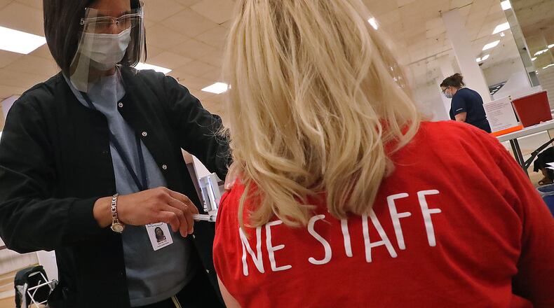 A member of the Northeastern High School staff gets the COVID-19 vaccine from nurse Salimah Berrien in the Clark County vaccine distribution center at the Upper Valley Mall in February. Vaccinated people are driving down coronavirus cases, hospitalizations and deaths in Ohio, leading Gov. Dewine to lift the state of emergency effective Friday. BILL LACKEY/STAFF