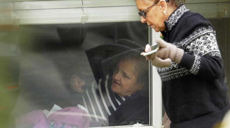 Carmen Gray, right, talks with her mother, Susan Hailey, left, who has tested positive for the new coronavirus, through the window of Hailey’s room at the Life Care Center in Kirkland, Wash., Tuesday, March 17, 2020, near Seattle. In-person visits are not allowed at the nursing home, at the center of the outbreak of new coronavirus. (AP Photo/Ted S. Warren)
