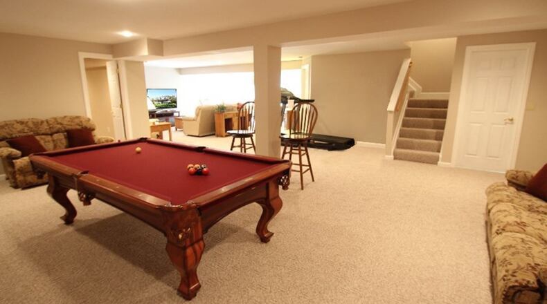 Berber carpet covers the floor in the open recreation/gathering area on the walkout lower level, which connects to the patio through sliding glass doors.