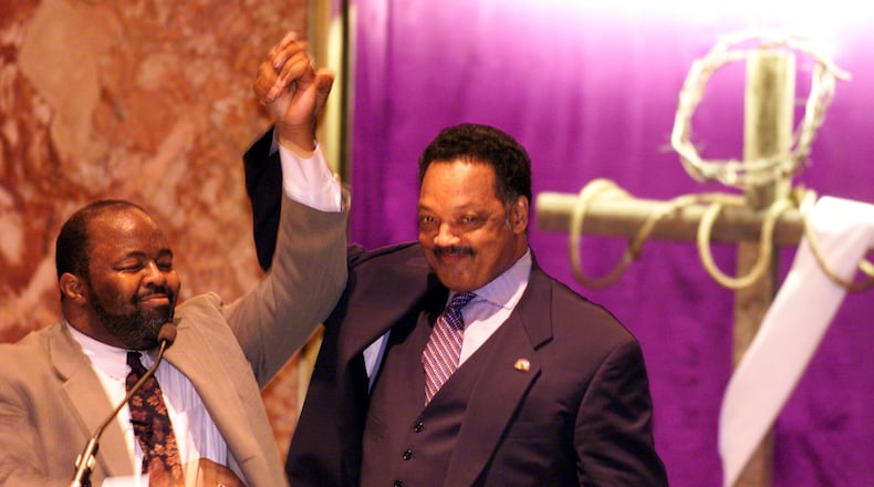 The Rev. Jesse Jackson, right, raises a triumphant arm with Daryl Ward, former pastor of the Omega Baptist Church, as Jackson takes the podium at the church to talk with the congregation. Jackson was making his way across Ohio from Cincinnati to Youngstown encouraging people to register to vote. STAFF