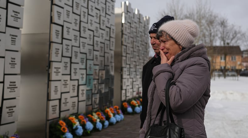 Relatives of those killed during the Russian occupation react at the Wall of Remembrance during a ceremony to mark the fourth anniversary of the Russian invasion of Ukraine, in Bucha, Ukraine, Tuesday, Feb. 24, 2026. (AP Photo/Sergei Grits)