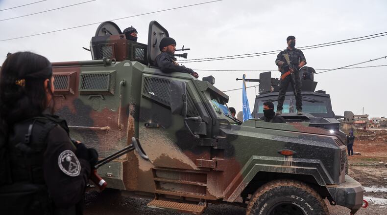 Kurdish-led Syrian Democratic Forces (SDF) soldiers, left and right, stand along the road as vehicles carrying a contingent of Syria's Interior Ministry security forces arrive to implement an agreement with the SDF aimed at stabilizing a ceasefire in al-Hassakeh, eastern Syria, Monday, Feb. 2, 2026. (AP Photo/Baderkhan Ahmad)