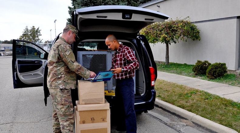 Staff Sgt. Chris Lineback (left) and Tech Sgt. Rommel Angeles, couriers at Wright-Patterson Air Force Base, complete a delivery Oct. 25. The Defense Courier Division is a joint-service operation responsible for the secure delivery of classified materials for the Department of Defense. (U.S. Air Force photo/Senior Airman Holly Ardern)