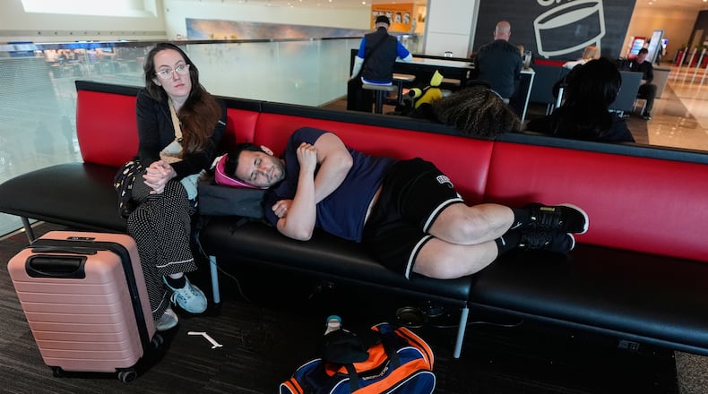 Jamie Sims left, and Carlos Serna, right, try to get some rest as they wait for their cancelled flight to El Paso, texas to be rescheduled at Love Field Airport in Dallas, Monday, March 16, 2026. (AP Photo/Tony Gutierrez)