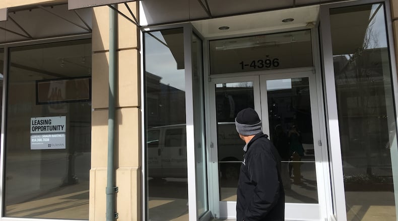 A shopper peers into an empty retail space at The Greene Town Center in Beavercreek. KARA DRISCOLL/STAFF