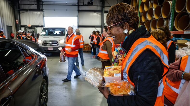 State Farm volunteer Linda Nervis, along with 25 other volunteers, helps load vehicles with food at the Dayton Foodbank Thursday morning, Nov. 17, 2022. JIM NOELKER/STAFF