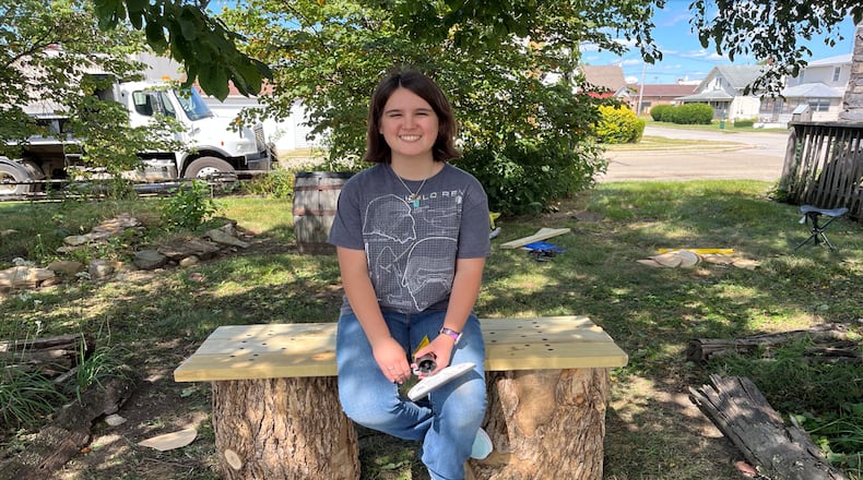 Kristen Hildebrecht, 17, smiles while sitting on one of two benches she made for the Mercer-Smith House in Fairborn. Hildebrecht is the first female Eagle Scout in the city. CONTRIBUTED