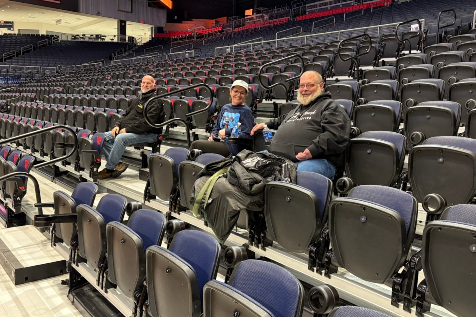 About the only three fans in the stands Sunday were (left to right): Rand Ney, the Buckeye Charters driver who drove the team bus for what ended up being a three-day stay by the Rhode Island women's team; Donna Ball, called Grandma Donna by Rams star Brooklyn Gray, and Bryan Arman. Ball and Arman came from Toledo to support Gray and were able to get into the Arena to become the Rams entire cheering section on Sunday, Jan. 26, 2026 at UD Arena. TOM ARCHDEACON / CONTRIBUTED PHOTO