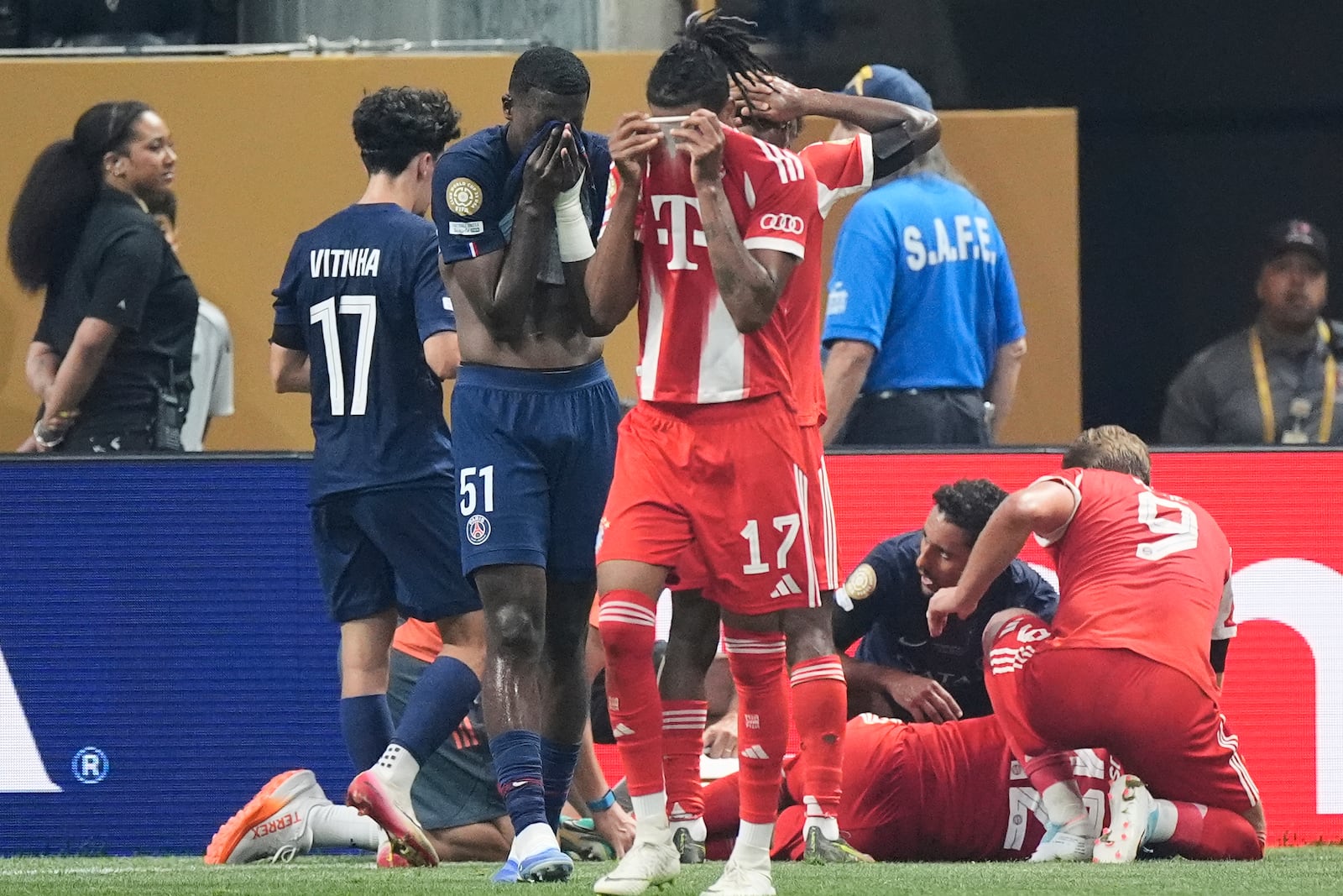 Bayern Munich's Michael Olise, foreground, and Paris Saint-Germain's Willian Pacho cover their faces while Bayern Munich's Jamal Musiala lies on the ground during the Club World Cup quarterfinal soccer match between PSG and Bayern Munich in Atlanta, Saturday, July 5, 2025. (AP Photo/Mike Stewart)