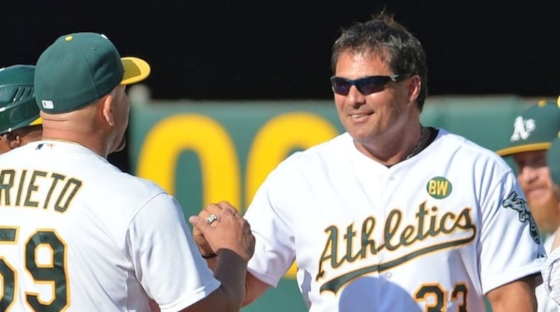 Oakland Athletics coach Ariel Prieto, left, congratulates former A's player Jose Canseco during a pregame celebration honoring the 1989 World Series championship team before the start of play against the Baltimore Orioles at O.Co Coliseum in Oakland, Calif., on Saturday, July 19, 2014. (Doug Duran/Bay Area News Group/MCT)