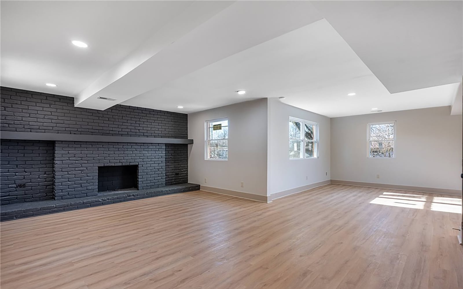 The family room has LVT flooring, recessed lighting and a full wall brick fireplace with a wood mantel. CONTRIBUTED