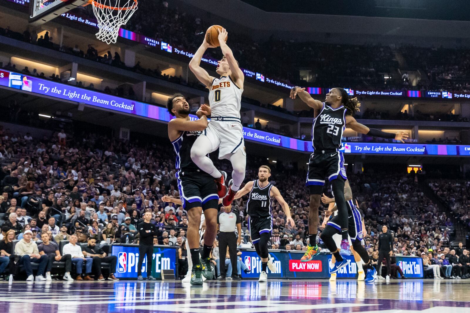 Denver Nuggets guard Christian Braun (0) goes up for a layup as Sacramento Kings forward Trey Lyles, left, defends during the first half of an NBA basketball game Wednesday, April 9, 2025, in Sacramento, Calif. (AP Photo/Sara Nevis)