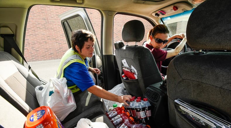 Jennifer Klumb, right, watches as Kroger employee Sabrina Barker loads her online grocery order into her vehicle as part of the Clicklist store pickup system Thursday, Sept. 8 at Kroger Marketplace on Yankee Road in Liberty Township. Customers can order their groceries online and pay and get their order loaded into their car by Kroger staff. NICK GRAHAM/STAFF