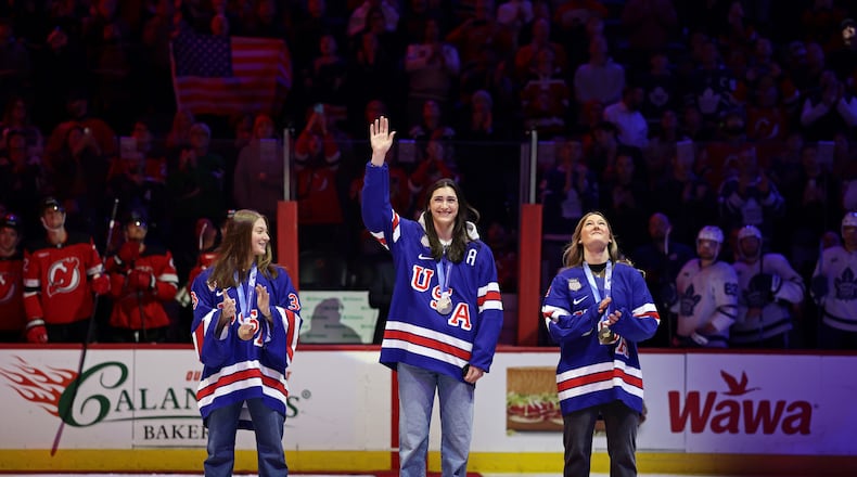 United States women's gold medal hockey players Megan Keller, center, Aerin Frankel, left, and Haley Winn, right, acknowledge the crowd before a ceremonial puck drop ahead of an NHL hockey game Wednesday, March 4, 2026, in Newark, N.J. (AP Photo/Adam Hunger)