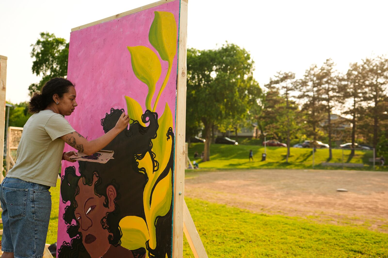 Eva Ngono works on a painting in a park near George Floyd Square on the five-year anniversary of Floyd's death, Sunday, May 25, 2025, in Minneapolis. (AP Photo/Abbie Parr)