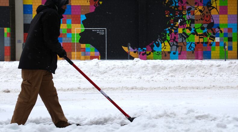 Kevin Daniels shovels snow and ice off the sidewalk along Jefferson Street in Dayton Friday.