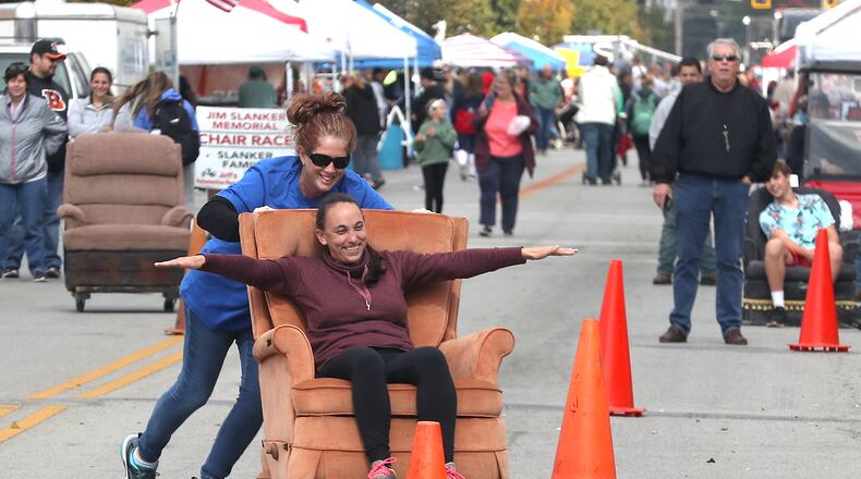 Lindsey Woods holds out her arms as Val Herdman pushes her in a recliner on wheels down Main Street in New Carlisle Sunday, Oct. 2, 2022. One of the highlights of the New Carlisle Heritage of Flight Festival every year is the Jim Slanker Memorial Chair Races. BILL LACKEY/STAFF