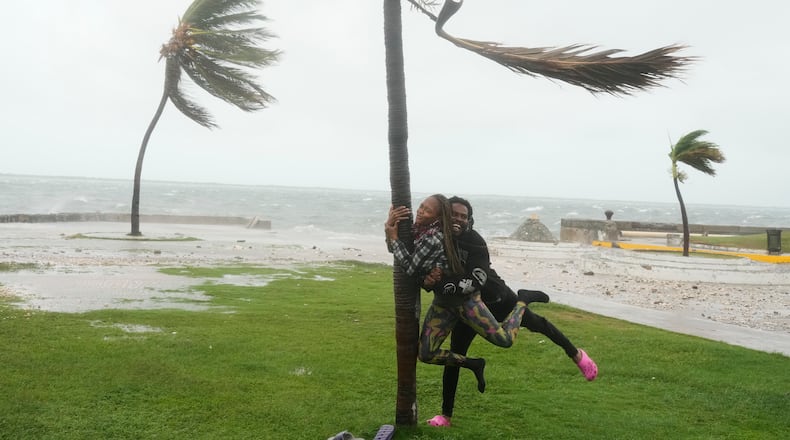 A couple jokes around on the coast in Kingston, Jamaica, as Hurricane Melissa approaches, Tuesday, Oct. 28, 2025. (AP Photo/Matias Delacroix)