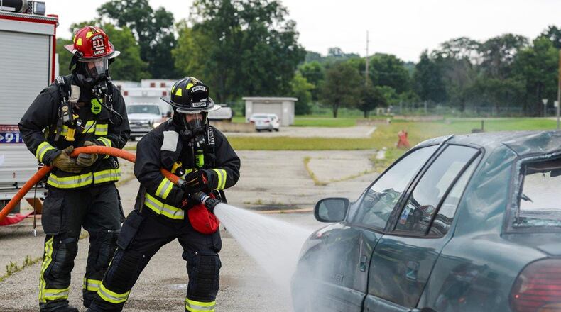 Firefighters from the 788th Civil Engineer Fire Department hose down a car that is supposed to be on fire on the scene of a simulated major crash during a base exercise at Wright-Patterson Air Force