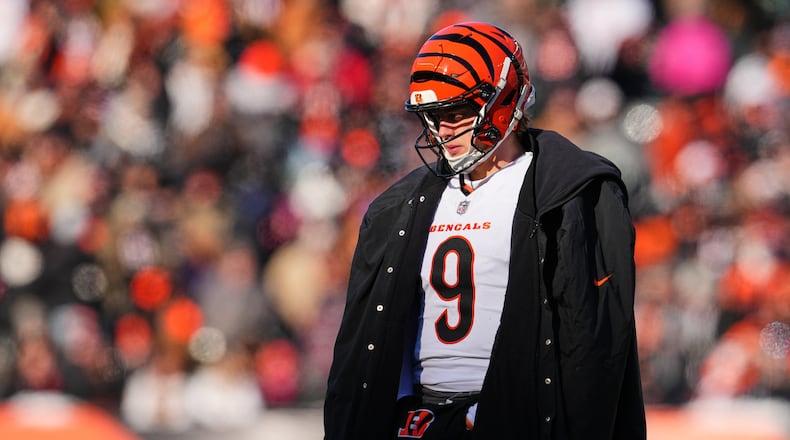 Cincinnati Bengals quarterback Joe Burrow (9) wears a sideline cape during a time out in the first half of an NFL football game against the Baltimore Ravens, Sunday, Dec. 14, 2025, in Cincinnati. (AP Photo/Jeff Dean)