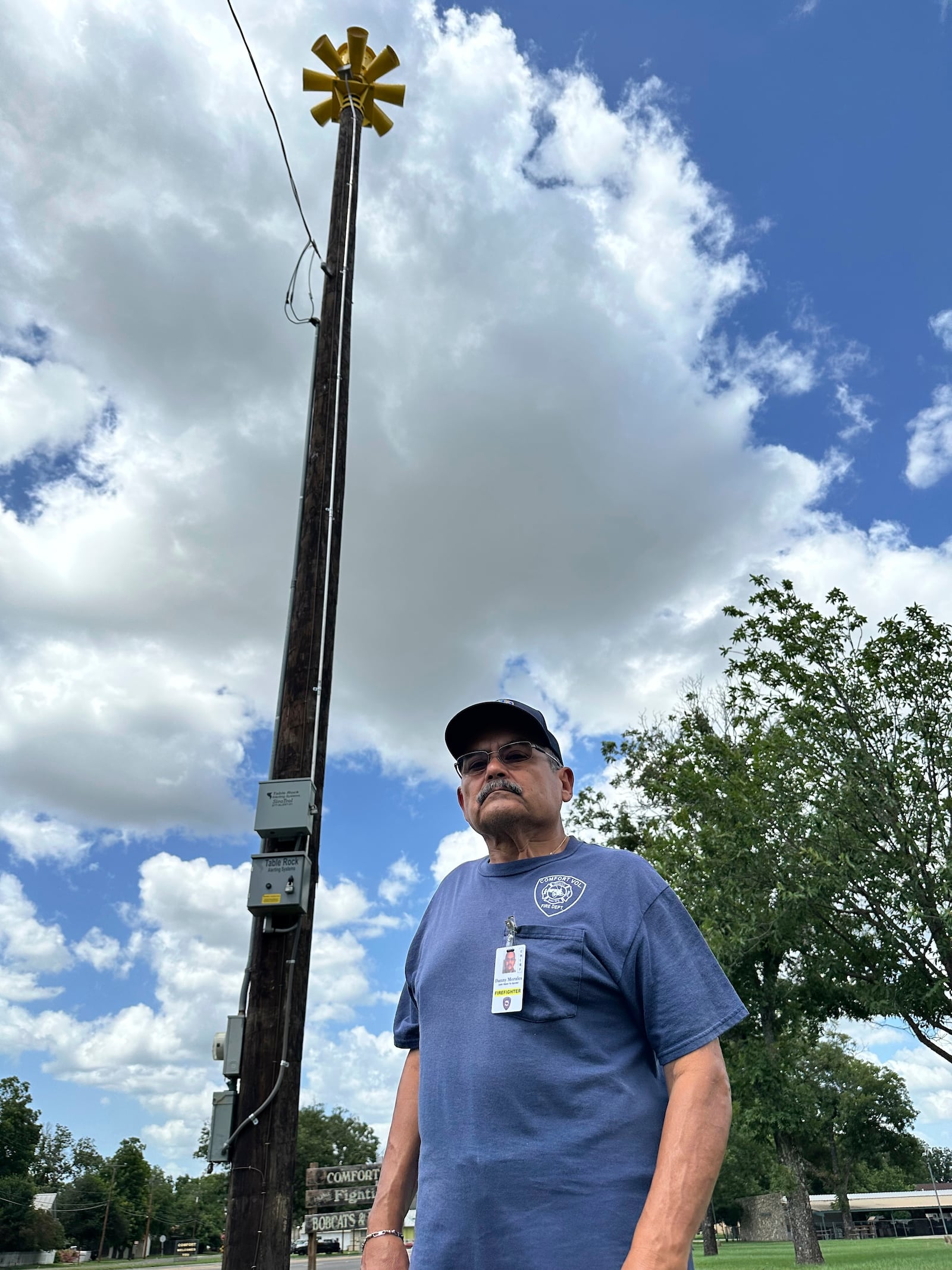 Comfort, Texas, Assistant Fire Chief, Danny Morales stands under a flash flood siren in the community's park on Thursday, July 10, 2025. (AP Photo/Sean Murphy)
