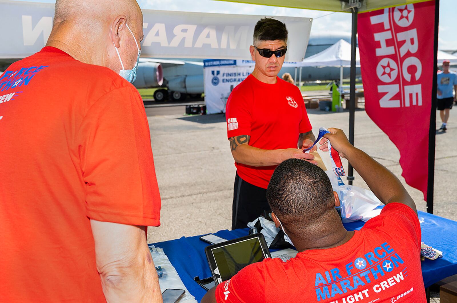 Douglas Suazo picks up his race packet for the Air Force Marathon on Sept. 17 from race volunteers Derrick Samuel (right) and William Riffle at the National Museum of the U.S. Air Force air park. U.S. AIR FORCE PHOTO/R.J. ORIEZ