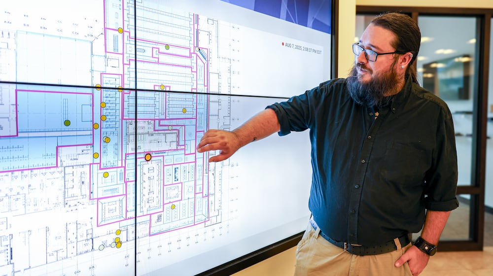 Tim Reynolds, a senior engineer for Stratacache company Walkbase, explains how a system of trackers on shopping carts can monitor customers in stores while standing at a map on display screens last August at Stratacache's experience center on the first floor of the former KeyBank Tower, across Main Street from Stratacache Tower. BRYANT BILLING / STAFF