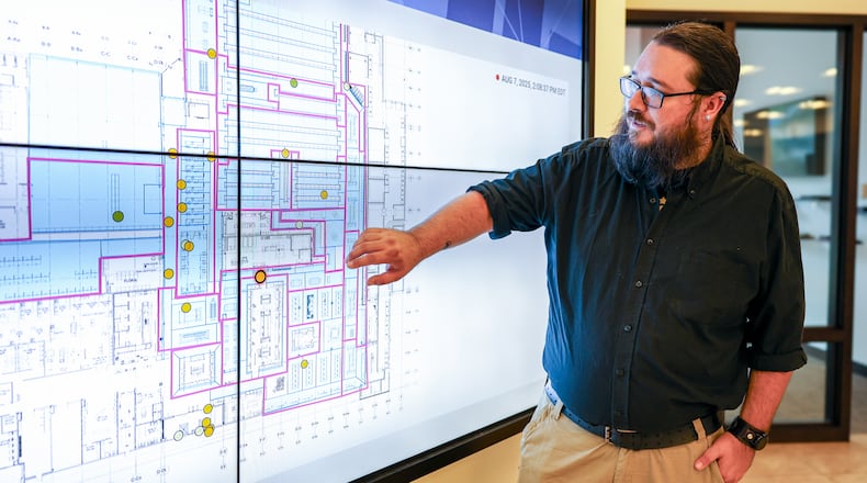 Tim Reynolds, a senior engineer for Walkbase, explains how a system of trackers on shopping carts can monitor customers in stores while standing at a map on display screens on Thursday, Aug. 7, at Stratacache's experience center on the first floor of the former KeyBank Tower, across Main Street from Stratacache Tower. The tags can track customers in stores. BRYANT BILLING / STAFF