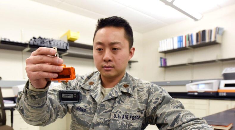 Maj. John Wang, health physicist, United States Air Force School of Aerospace Medicine Radiation Dosimetry Lab inspects a dual radiation dosimeter at Wright-Patterson Air Force Base Dec. 19, 2019. For the first time in nearly 40 years, U.S. Air Force personnel who work near radioactive materials will be receiving newly designed, higher-sensitivity radiation dosimeters designed and fielded by USAFSAM Radiation Dosimetry Lab. The dosimeters record the amount of exposure to ionizing radiation for individuals. U.S. AIR FORCE PHOTO/TY GREENLEES