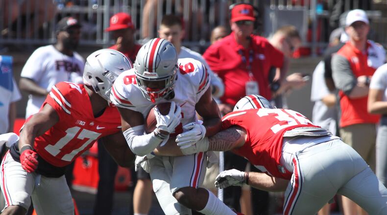 Ohio State’s Torrance Gibson, center, is tackled by Jerome Baker, left, and Zach Turnure during the spring game April 16 at Ohio Stadium in Columbus. David Jablonski/Staff
