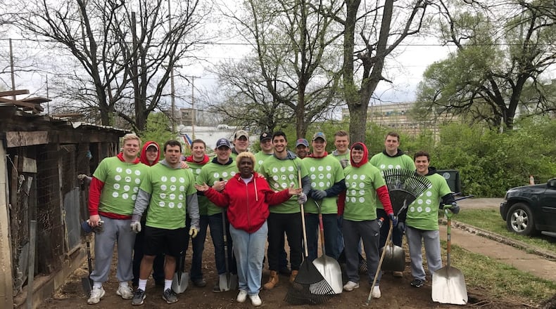 Annette Gibson-Strong is surrounded by the UD football players who helped clean up her Hopeland Street property and fix her home Saturday as part of the Rebuilding Together Dayton project in the Carillon Neighborhood near Welcome Stadium. Tom Archdeacon/STAFF
