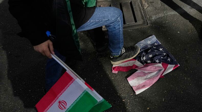A school boy stomps a U.S. flag as he holds an Iranian flag during an annual rally in front of the former U.S. Embassy in Tehran, celebrating the anniversary of the 1979 takeover of the embassy, Iran, Tuesday, Nov. 4, 2025. (AP Photo/Vahid Salemi)