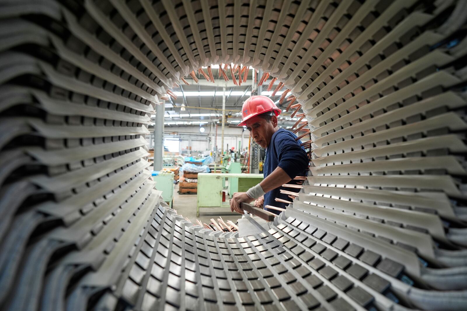 A worker inserts copper cables into an engine at a plant in Mexico City, Wednesday, April 2, 2025. (AP Photo/Fernando Llano)