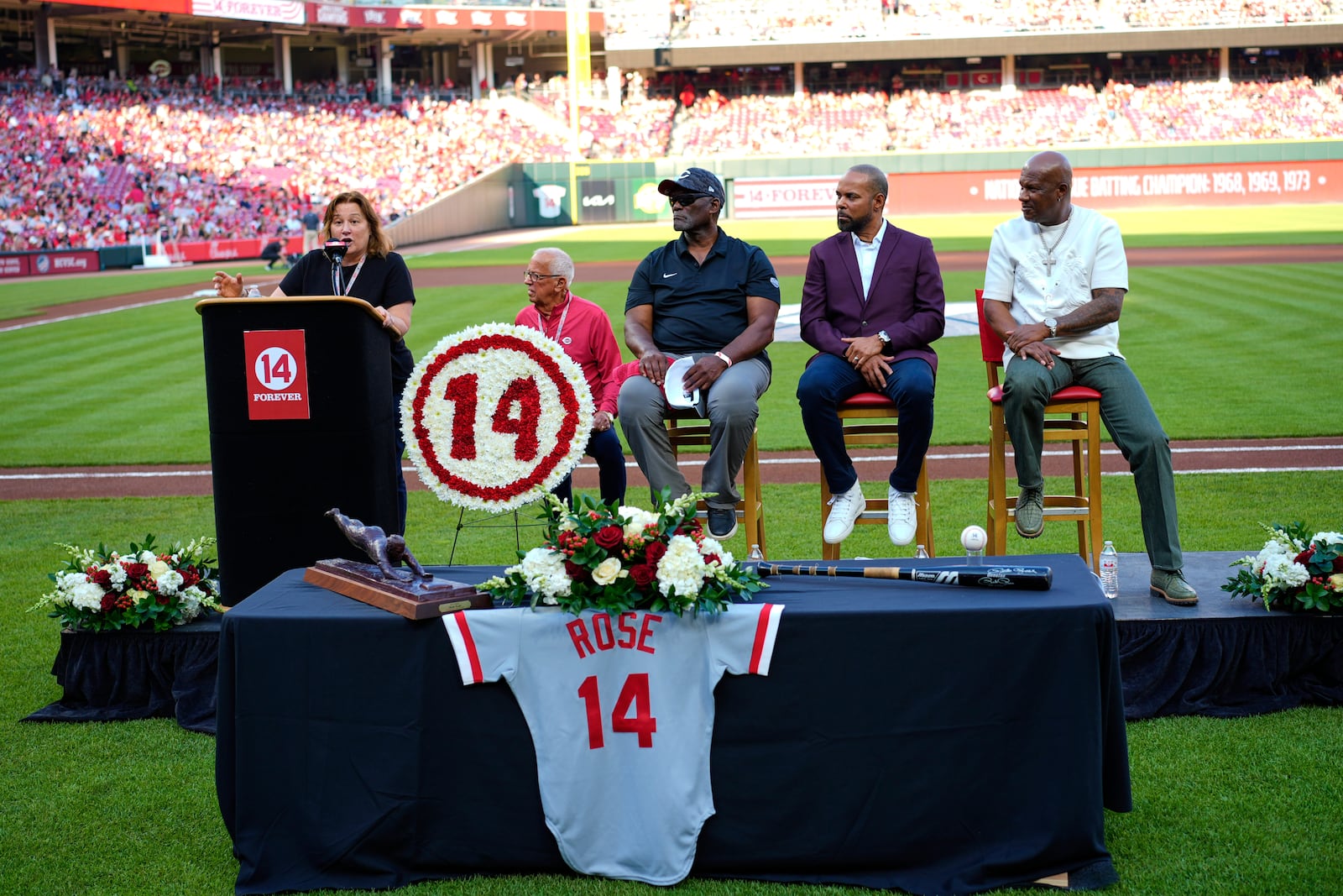 Pete Rose's daughter Fawn Rose speaks as Reds Hall of Fame players, left to right, George Foster, Barry Larkin and Eric Davis listen during Pete Rose Night events before a baseball game between the Cincinnati Reds and the Chicago White Sox, Wednesday, May 14, 2025, in Cincinnati. (AP Photo/Carolyn Kaster)