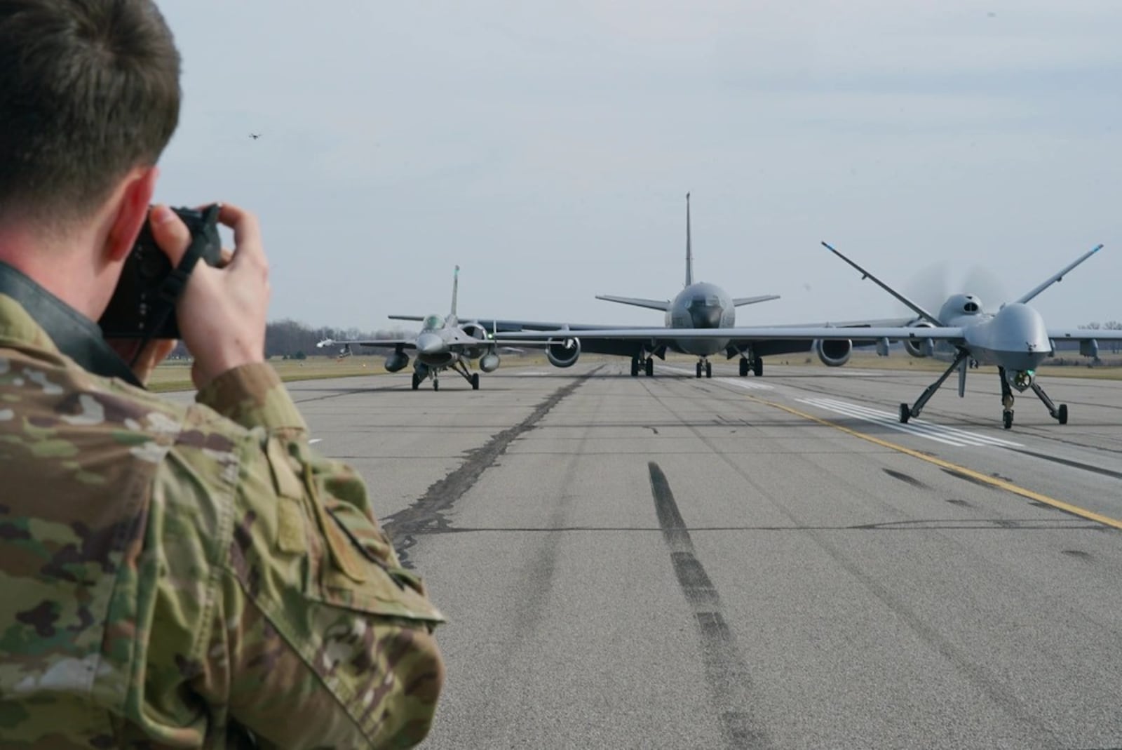 Airman 1st Class Josh Kaeser takes a photo of a F-16C Fighting Falcon, KC-135 Statotanker, and an MQ-9 Reaper, while the aircraft sit on the flight line, at Springfield-Beckley Air National Guard base on March 19, 2025. (U.S. Air National Guard photo by Staff Sgt. Jillian Maynus, 178th Wing)