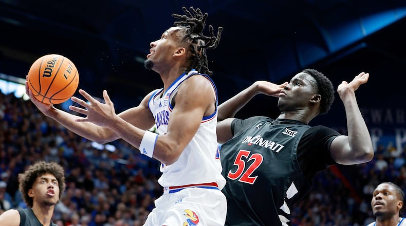 Kansas guard Darryn Peterson, left, attempts to score as Cincinnati center Moustapha Thiam (52) defends during the first half of an NCAA college basketball game, Saturday, Feb. 21, 2026, in Lawrence, Kan. (AP Photo/Colin E. Braley)
