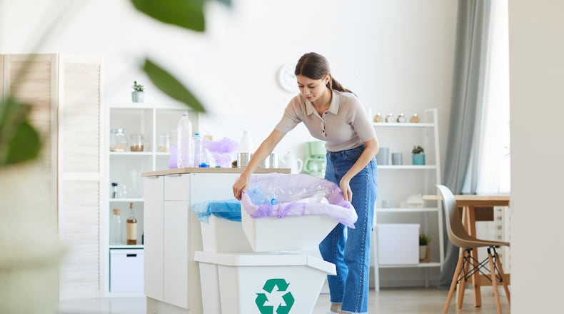 A woman throws out the garbage she bringing the bins in the kitchen. iSTOCK/COX