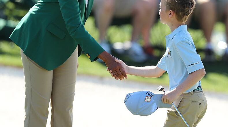 Carter Kontur, of Lawrenceville, is greeted by former Secretary of State (and Augusta National Golf Club member) Condoleezza Rice after putting on the 18th green during the Drive Chip & Putt National Finals at Augusta National Golf Club on Sunday, April 2. (Curtis Compton/ccompton@ajc.com)