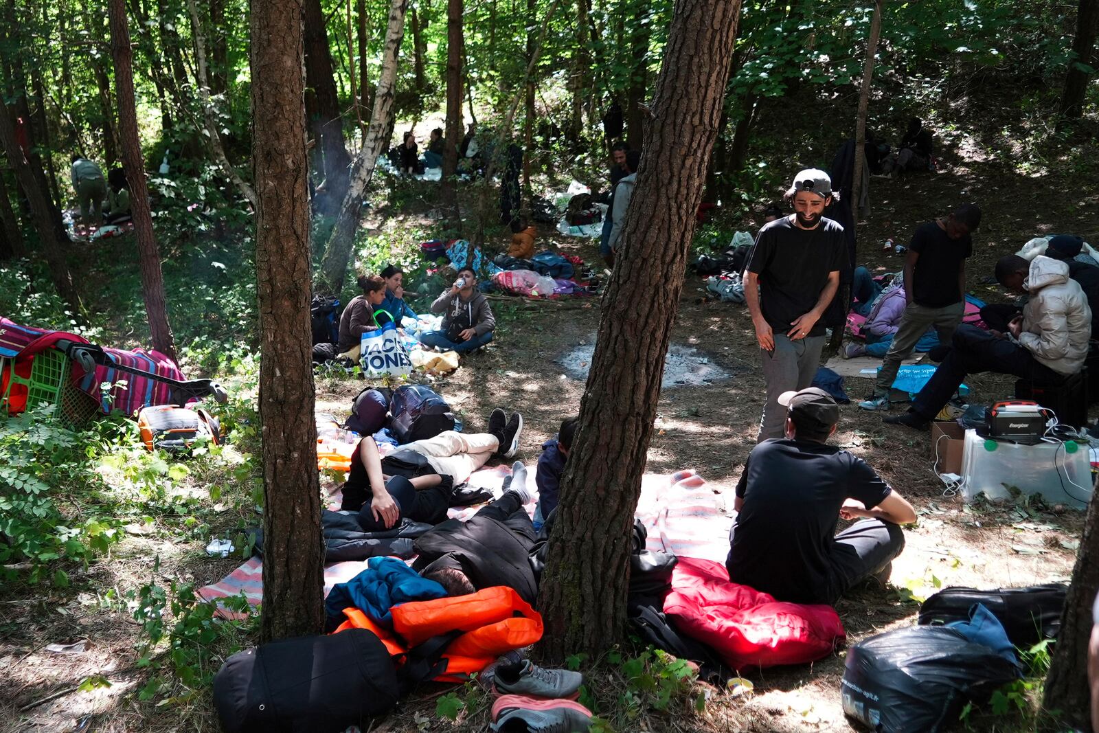 Migrants wait in the Ecault forest, northern France, Thursday, July 3, 2025. (AP Photo/Nicolas Garriga)