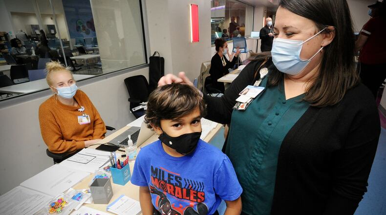 Roman Collier, age 10, waits with mother, Nikki, to receive his COVID-19 vaccine at Dayton Children's Monday, Nov. 8, 2021. MARSHALL GORBY\STAFF