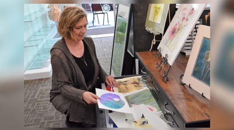 Artist Rusty Harden goes through some of her art work shortly after the opening of her new studio in downtown Tipp City. CONTRIBUTED