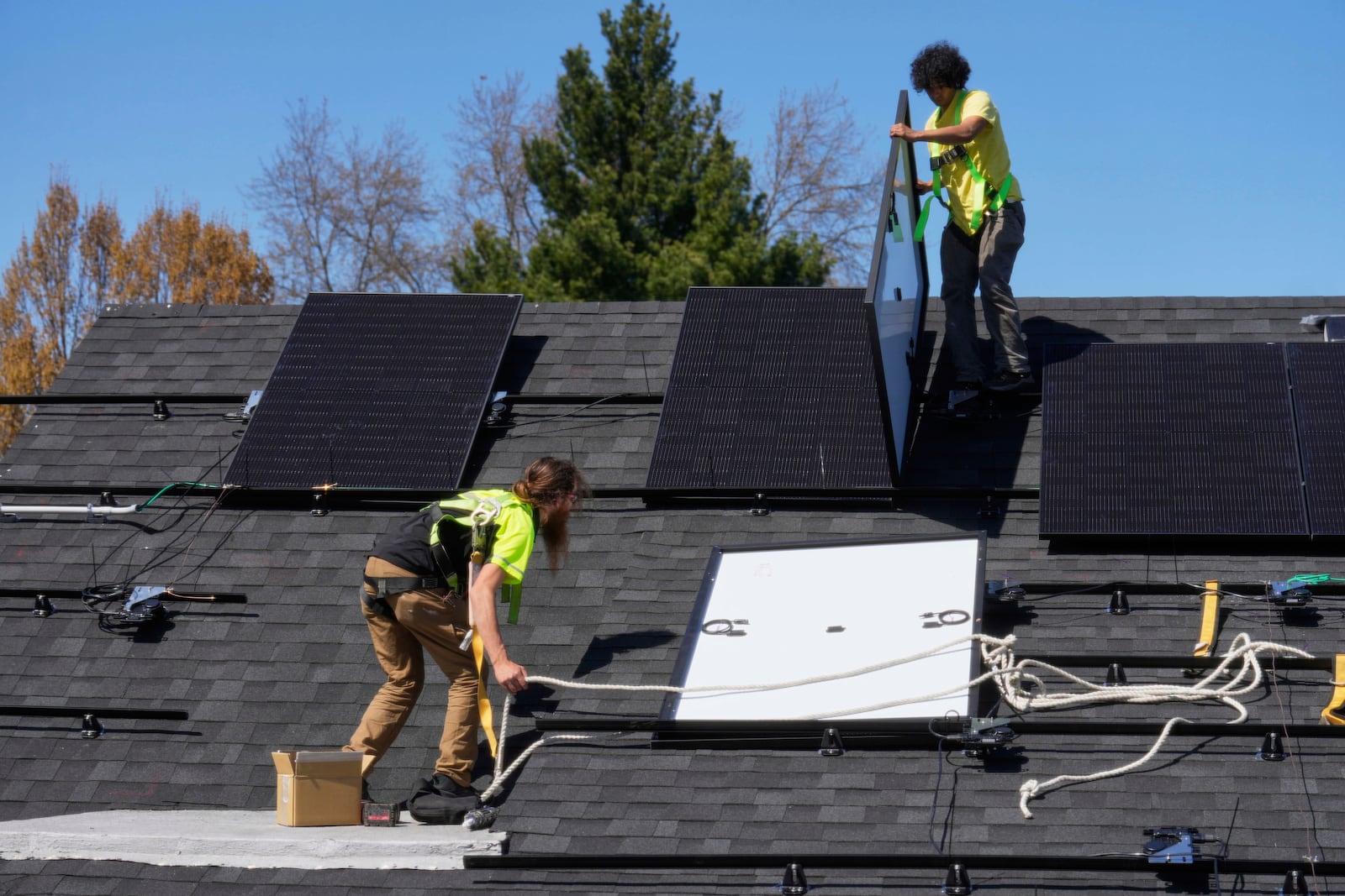 Theodore Tanczuk, left, and Brayan Santos, right, of solar installer YellowLite, put panels on the roof of a home in Lakewood, Ohio, Wednesday, April 16, 2025. (AP Photo/Sue Ogrocki)