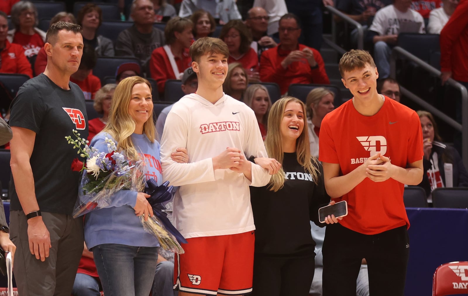 Aiden Derkack, right, claps as his brother Jordan, center, is introduced during Dayton's Senior Night ceremony on Friday, March 6, 2026, at UD Arena. Also pictured are Aiden's parents, Gene and Jenny, left of Jordan; and his sister Taylor, second from right. David Jablonski/Staff