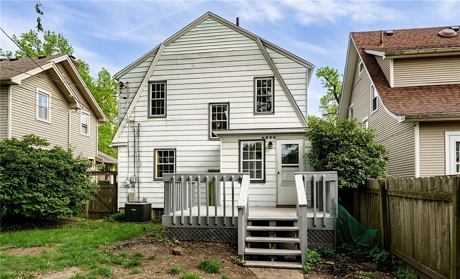 The rear of the home features a wood deck with railings and a full wood privacy fence.