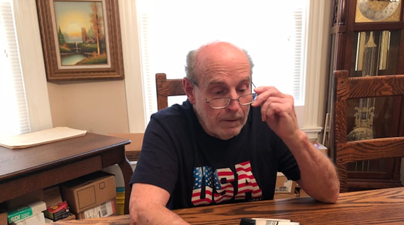 William Reed looks at photos during a recent interview. Reed was forced to declare bankruptcy because of medical bills caused by illness. MAX MILLIGAN / WRIGHT STATE UNIVERSITY