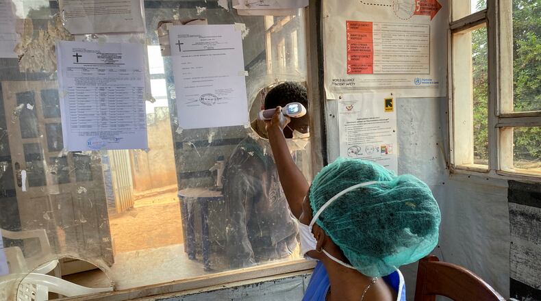 FILE - A medical worker checks a person's temperature at the Matanda Hospital in Butembo, where the first case of Ebola died, in the North Kivu province of Congo, Feb. 11, 2021. (AP Photo/Al-hadji Kudra Maliro)