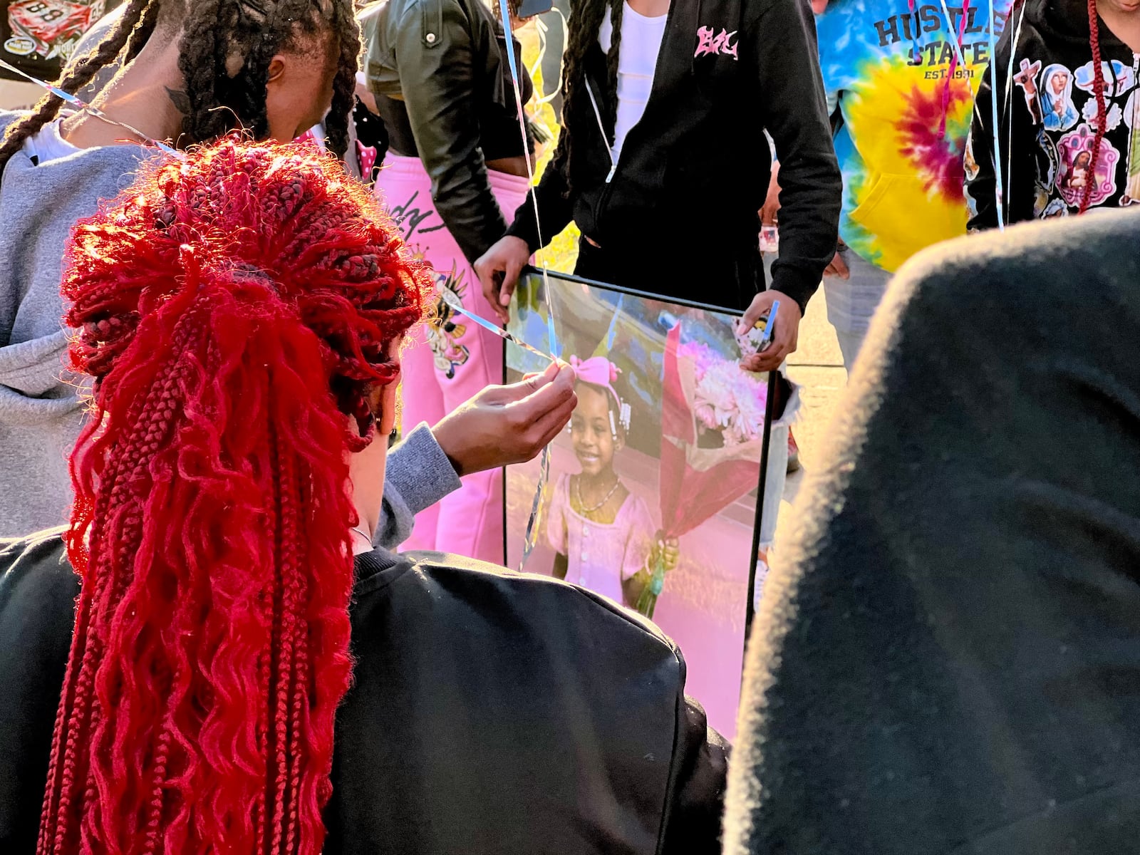 A loved one honoring Legaci Deshawn Taylor holds a framed picture of the 5-year-old during a memorial Sunday honoring the young girl who was killed in a shooting on Friday.